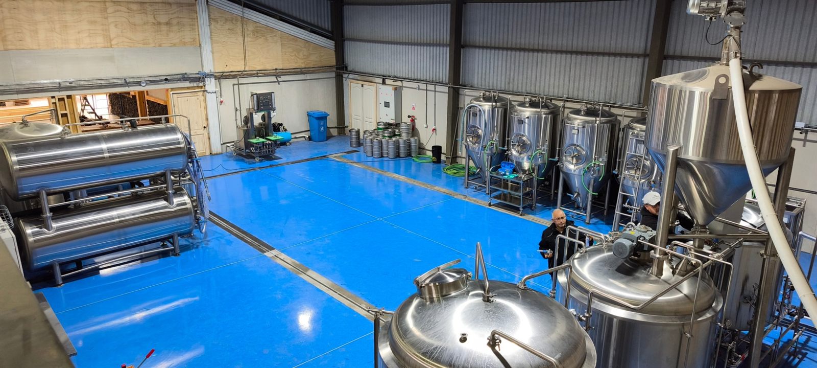 Sala de cocción y fermentación de una cervecería, con fermentadores cónicos, tanques y barriles